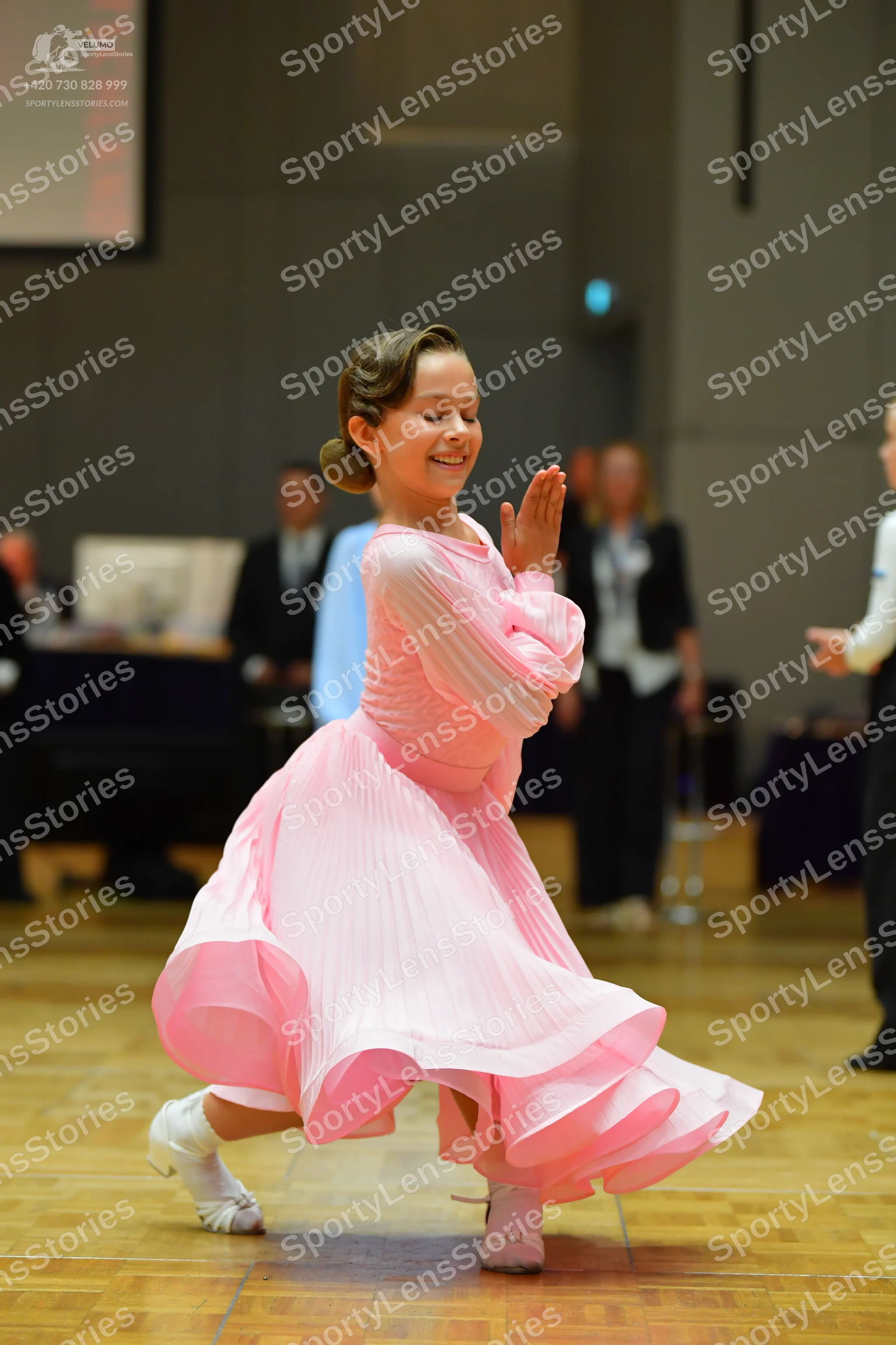 Dancesport competitor: Female dancer: pink ballroom dress with a voluminous ruffled skirt and pleated b