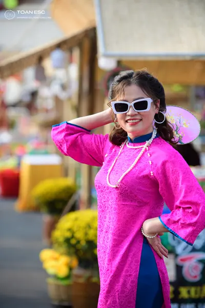Dancesport competitor: Female dancer: pink patterned long-sleeved tunic with blue trim, pearl necklace,