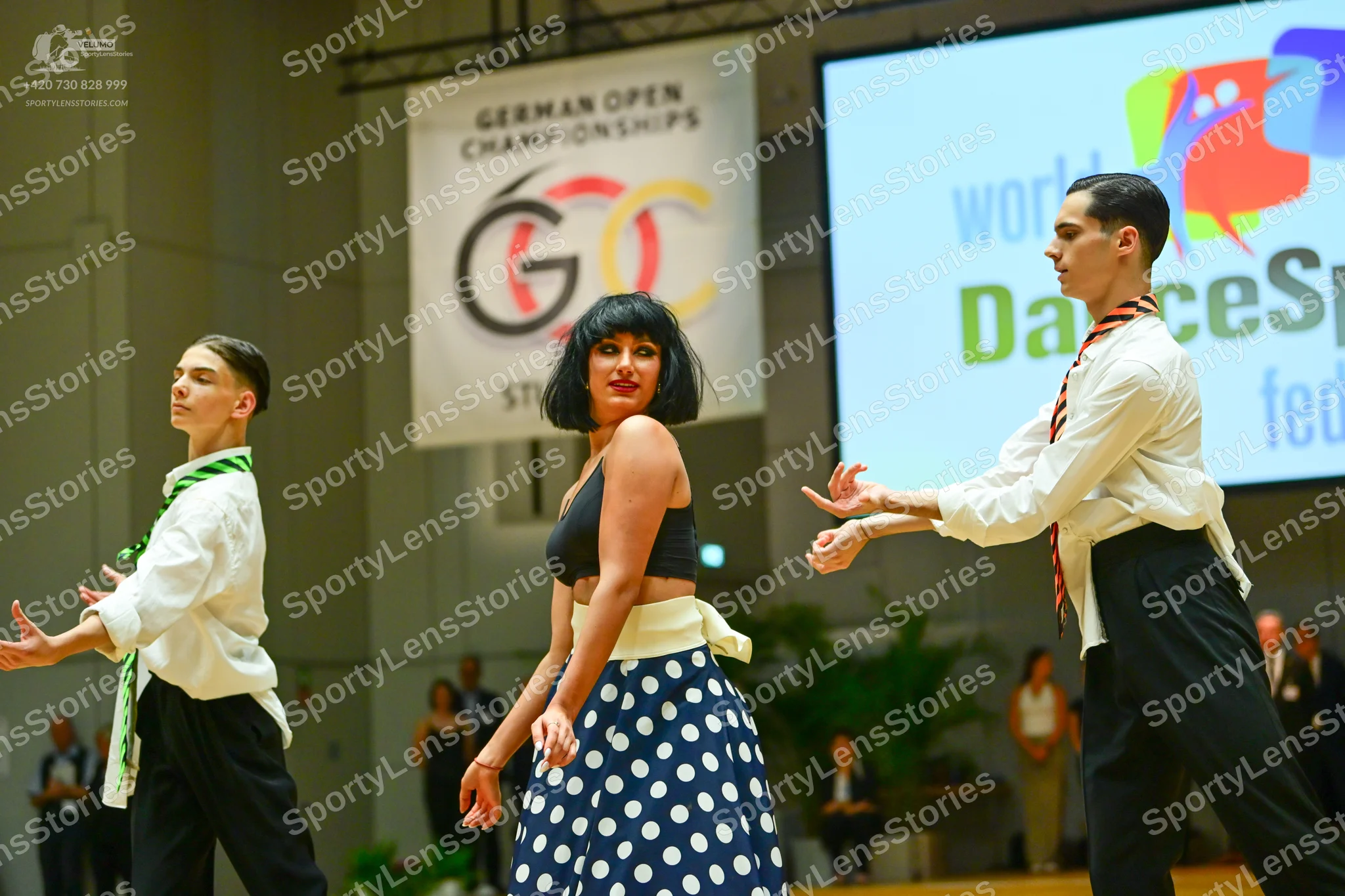 Dancesport competitor: Male dancer (left): white long-sleeved shirt, green and white patterned tie, and