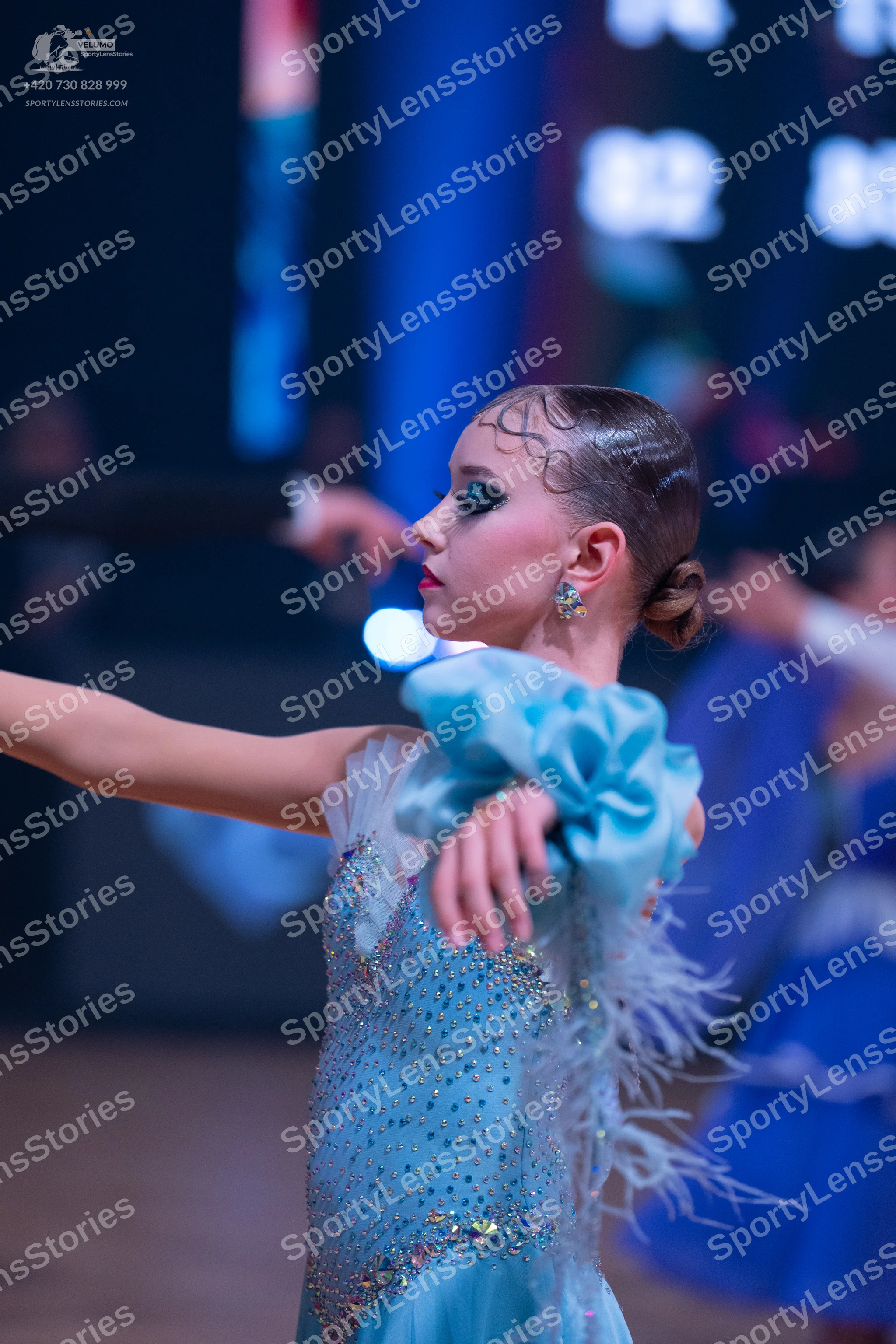 Dancesport competitor: Female dancer in foreground: light blue Latin dance dress with sequins, silver e