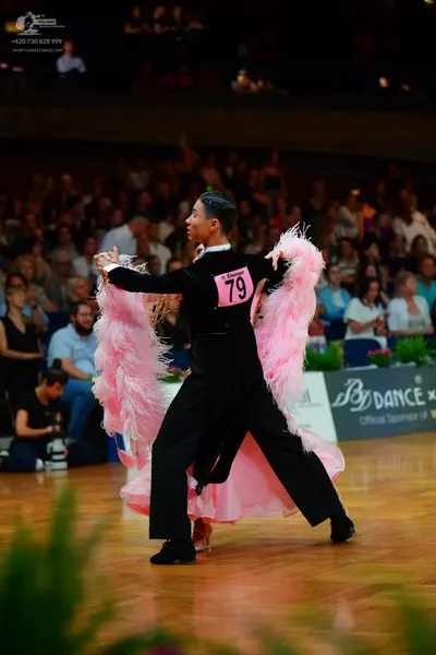 Dancesport competitor: Male dancer: black long-sleeved top and black trousers with a large, voluminous 