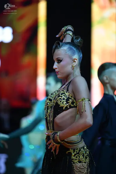 Dancesport competitor: Female dancer: black Latin dance costume with intricate gold sequin embroidery a