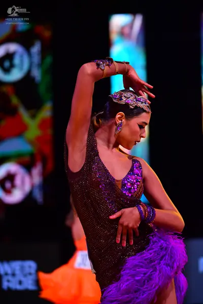 Dancesport competitor: Female dancer: dark purple/burgundy latin dress with sequins and purple feathers
