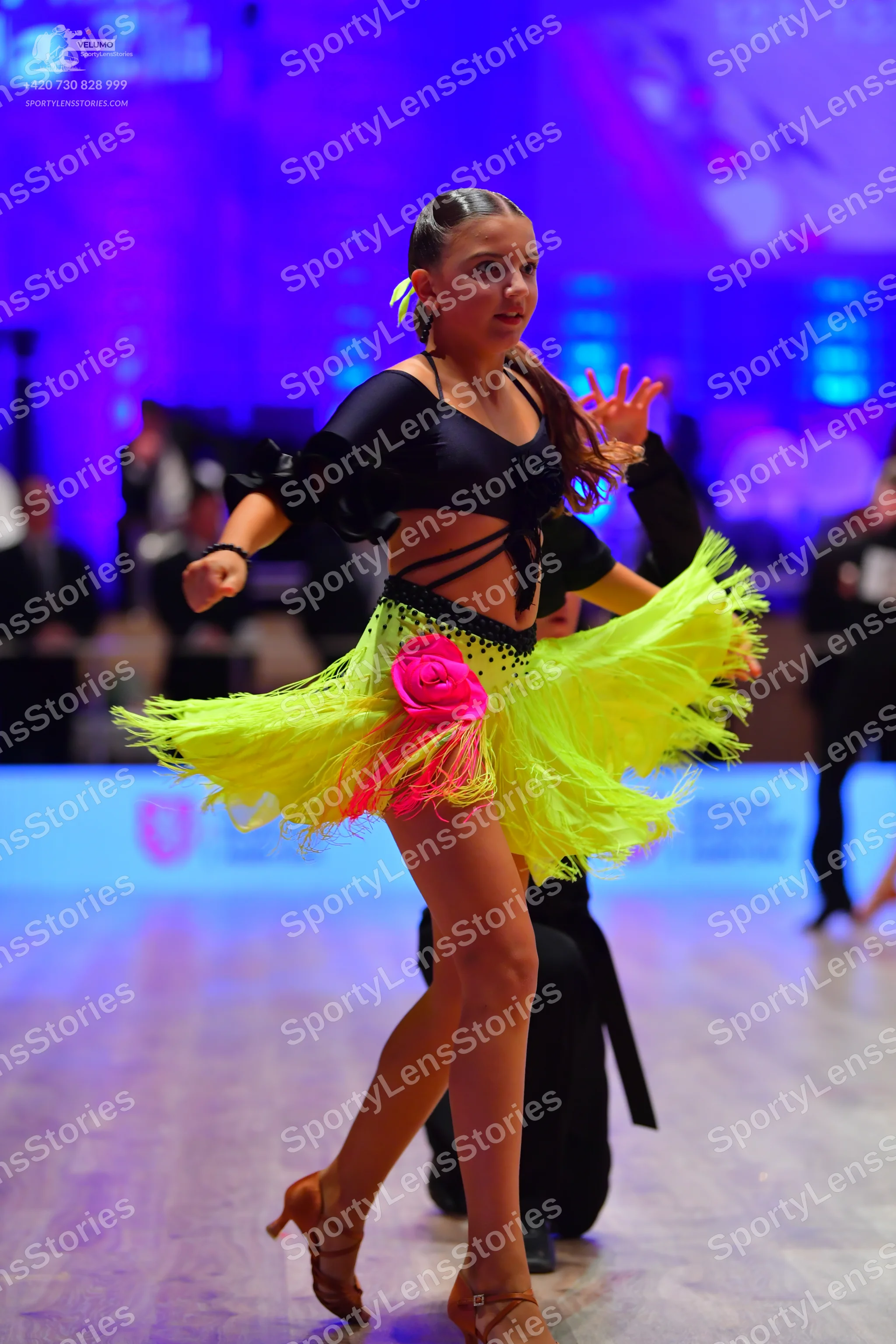 Dancesport competitor: Female dancer: black long-sleeved crop top and bright yellow latin dress with fr