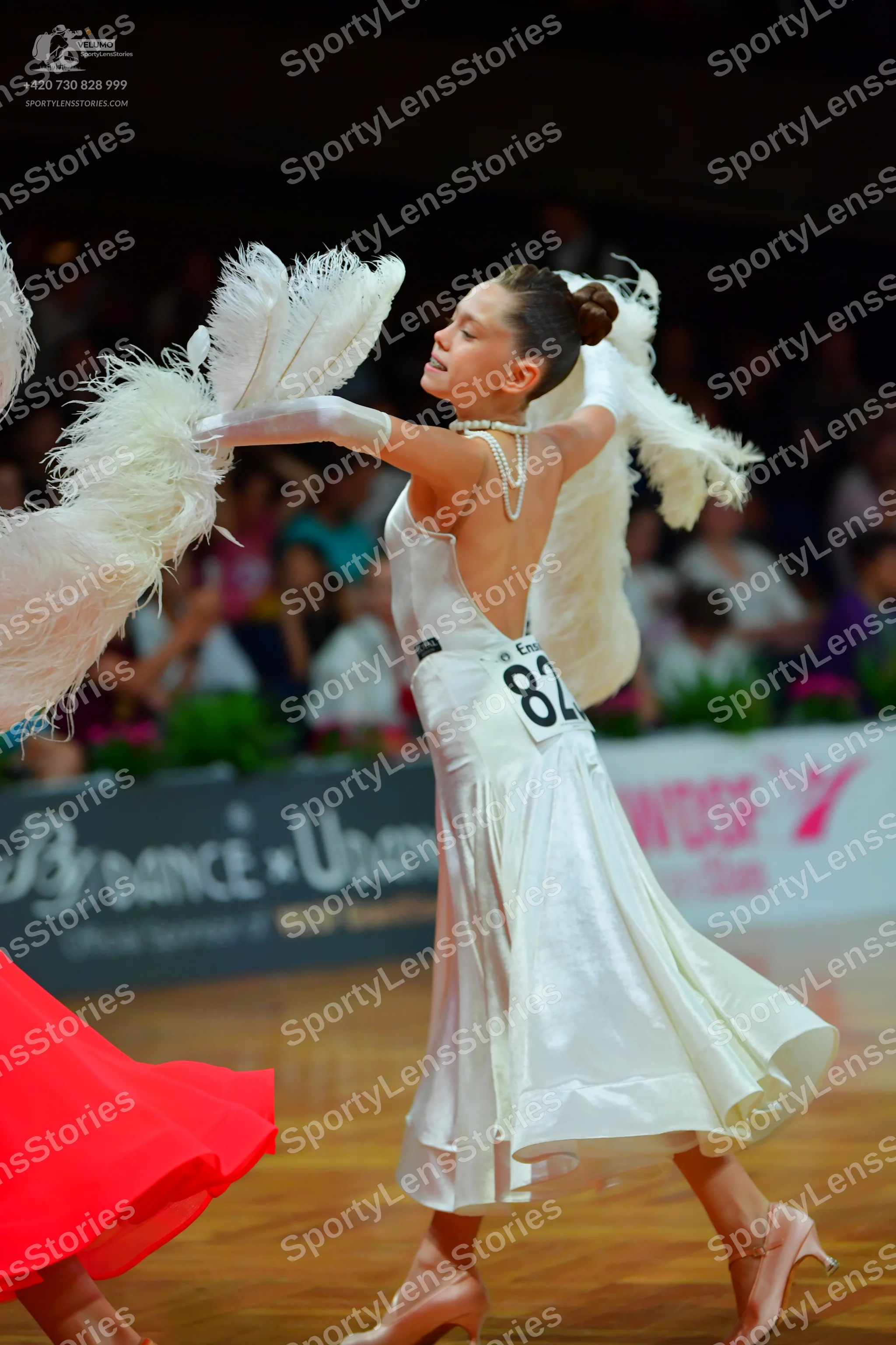 Dancesport competitor: Female dancer: white backless ballroom dress in a satin-like fabric, featuring l