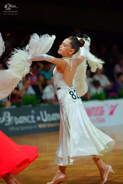 Dancesport competitor: Female dancer: white backless ballroom dress in a satin-like fabric, featuring l