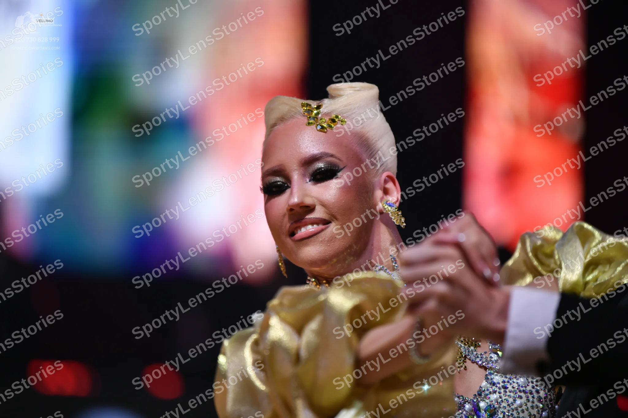 Dancesport competitor: Female dancer: gold-colored costume with voluminous, ruffled satin-like sleeves