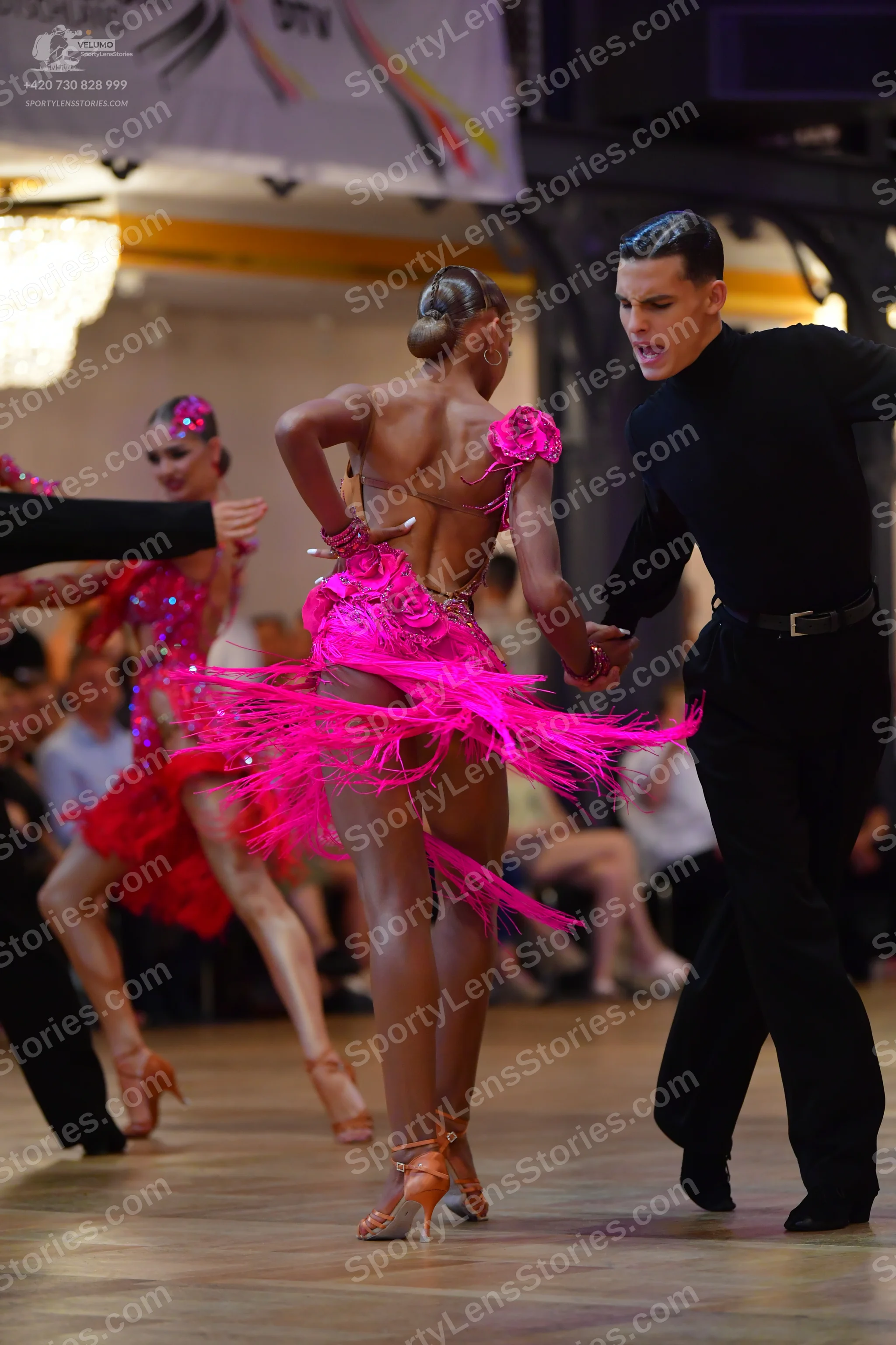 Dancesport competitor: Okay, here's a detailed description of the dancers’ costumes in the photo, forma