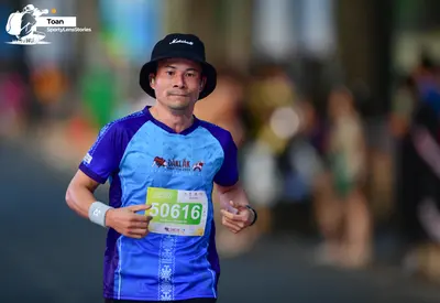Marathon runner #50616: Runner 1: blue and purple jersey, black bucket hat, white wristband