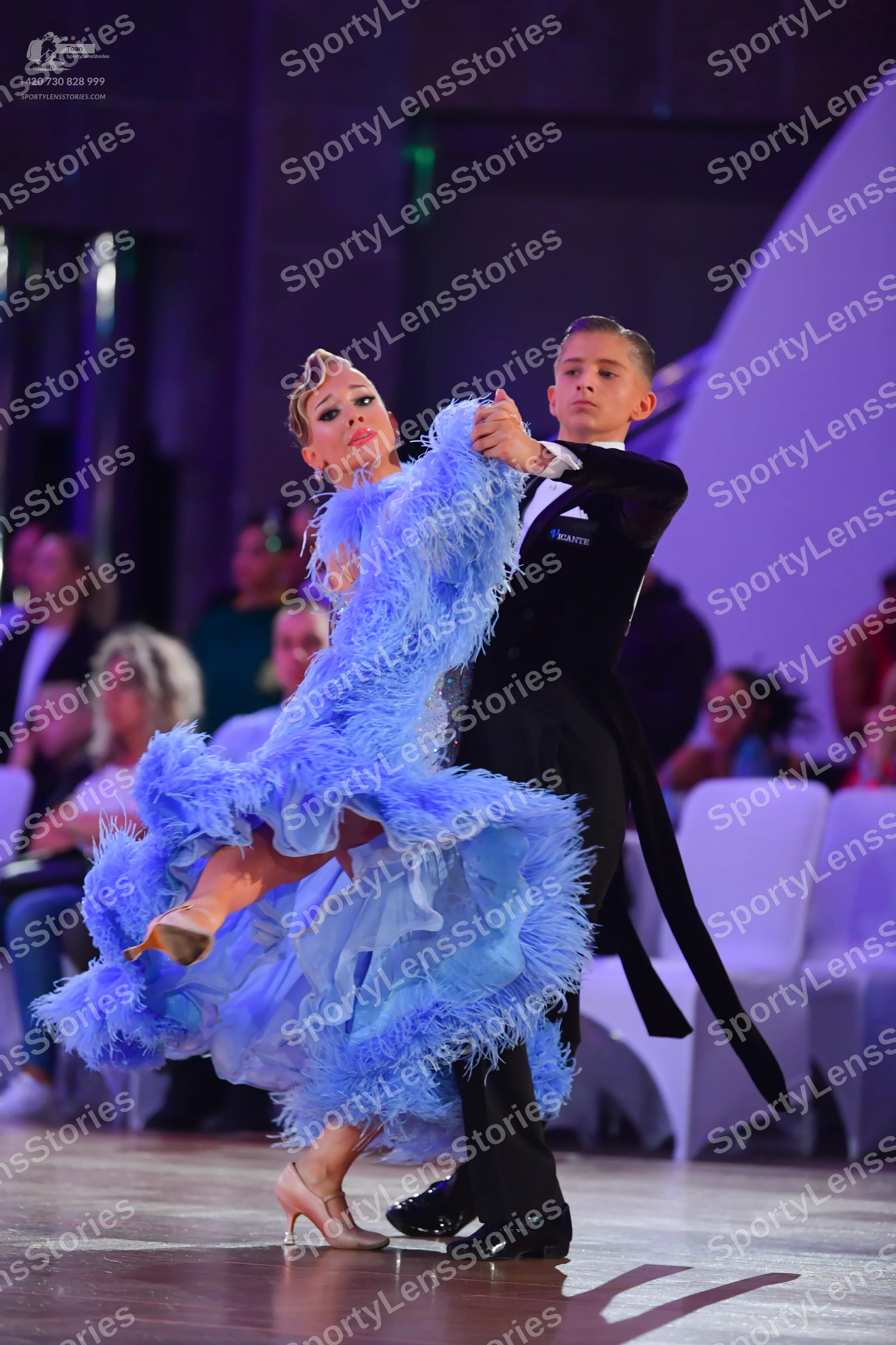Dancesport competitor: Female dancer: voluminous light blue ballroom dress with feather-like trim