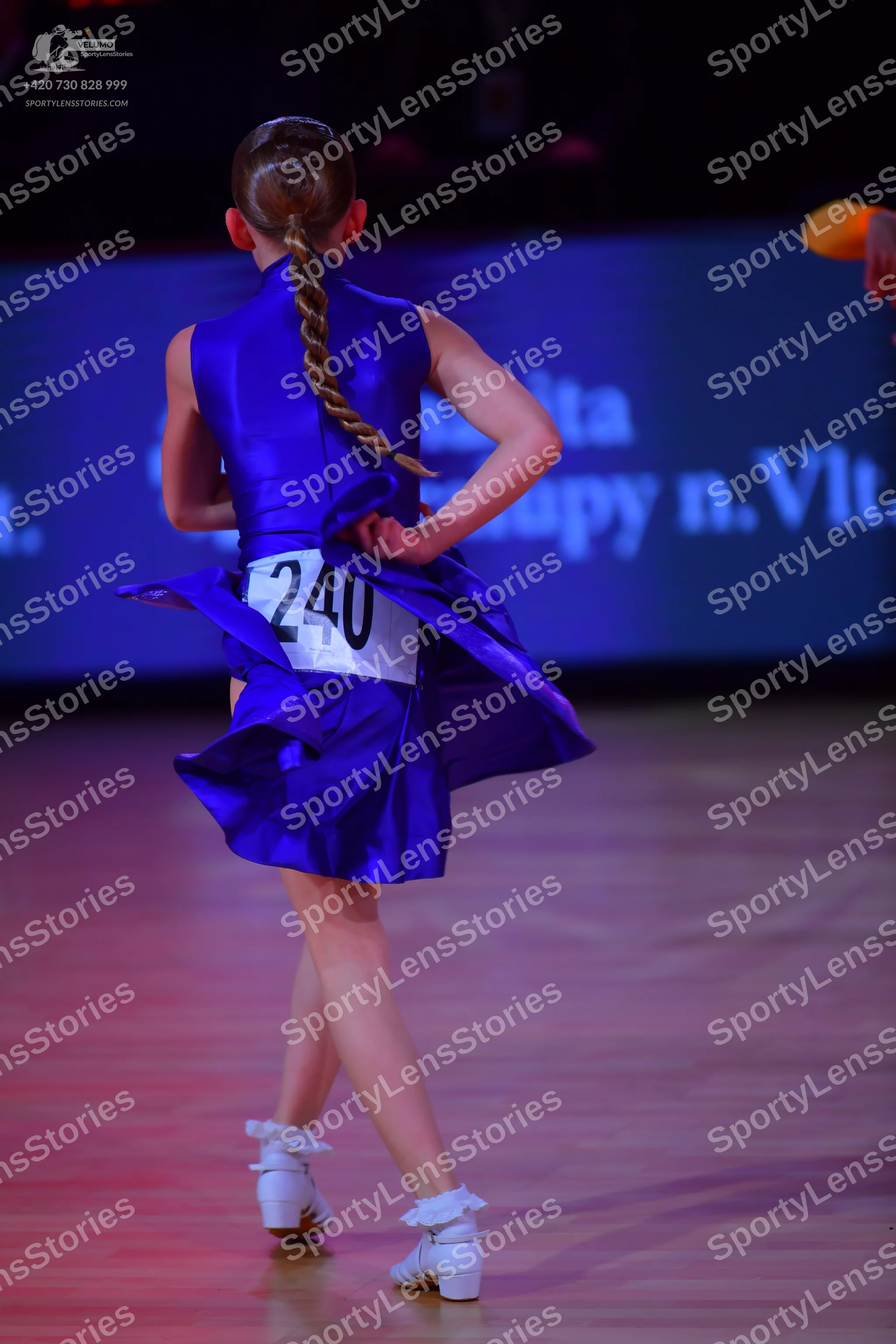Dancesport competitor: Female dancer: royal blue satin-like Latin dress with a flared skirt and white d