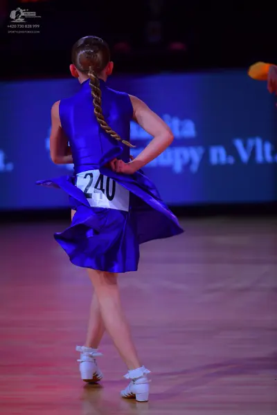 Dancesport competitor: Female dancer: royal blue satin-like Latin dress with a flared skirt and white d