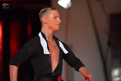 Dancesport competitor: Male dancer: black long-sleeved shirt with a large white collar and a black belt