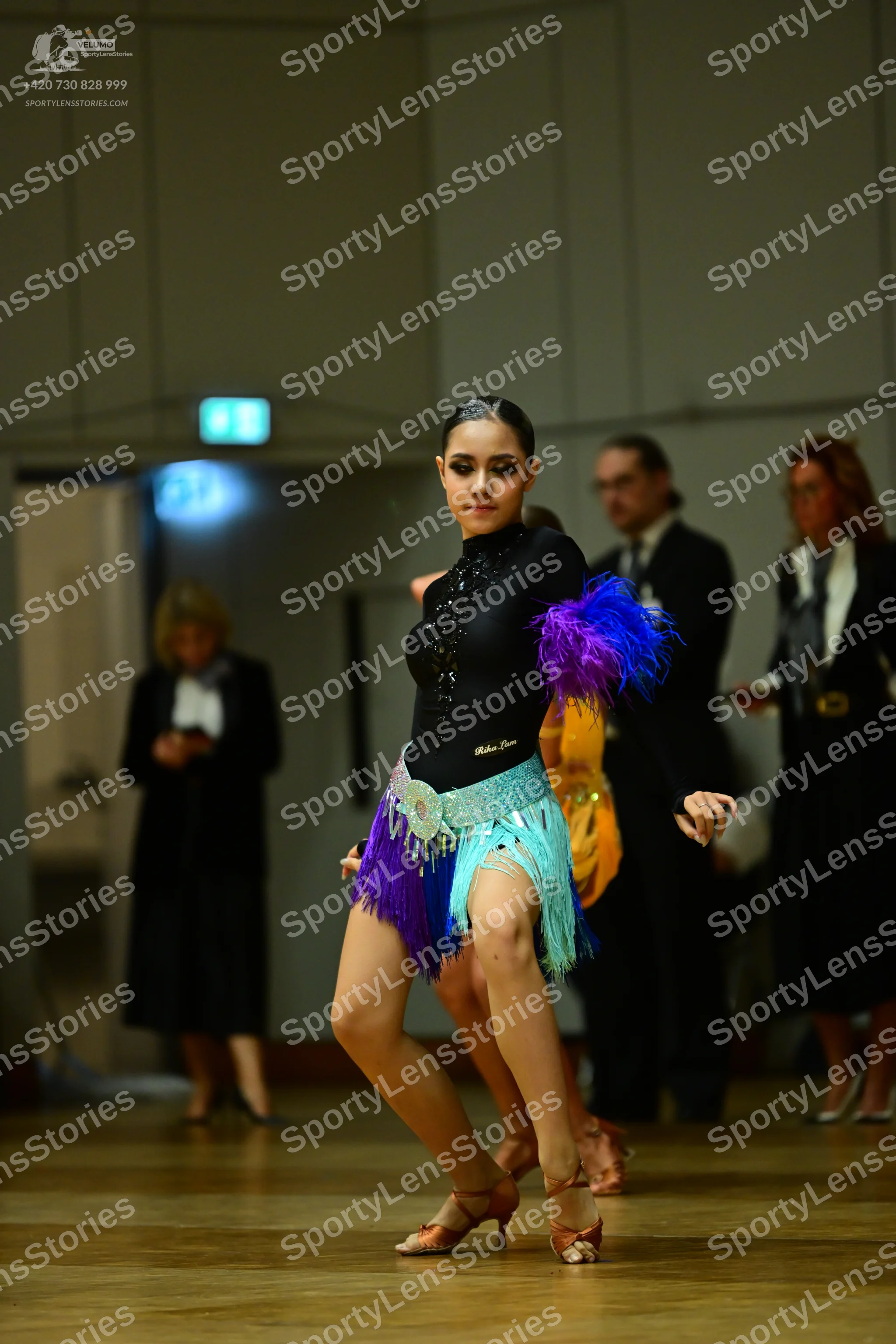 Dancesport competitor: Female dancer: black long-sleeved bodysuit with rhinestones, a multi-colored fri
