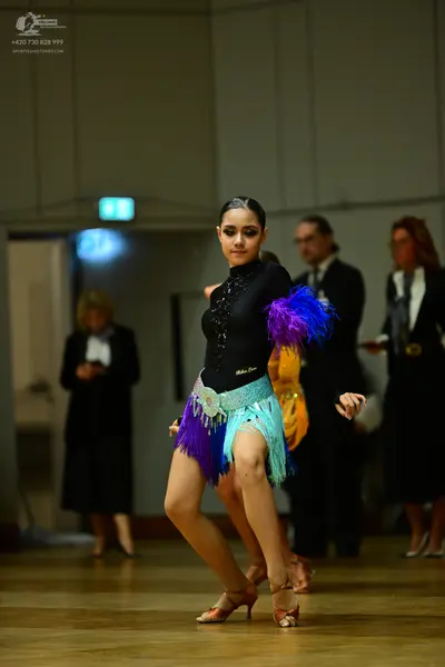 Dancesport competitor: Female dancer: black long-sleeved bodysuit with rhinestones, a multi-colored fri