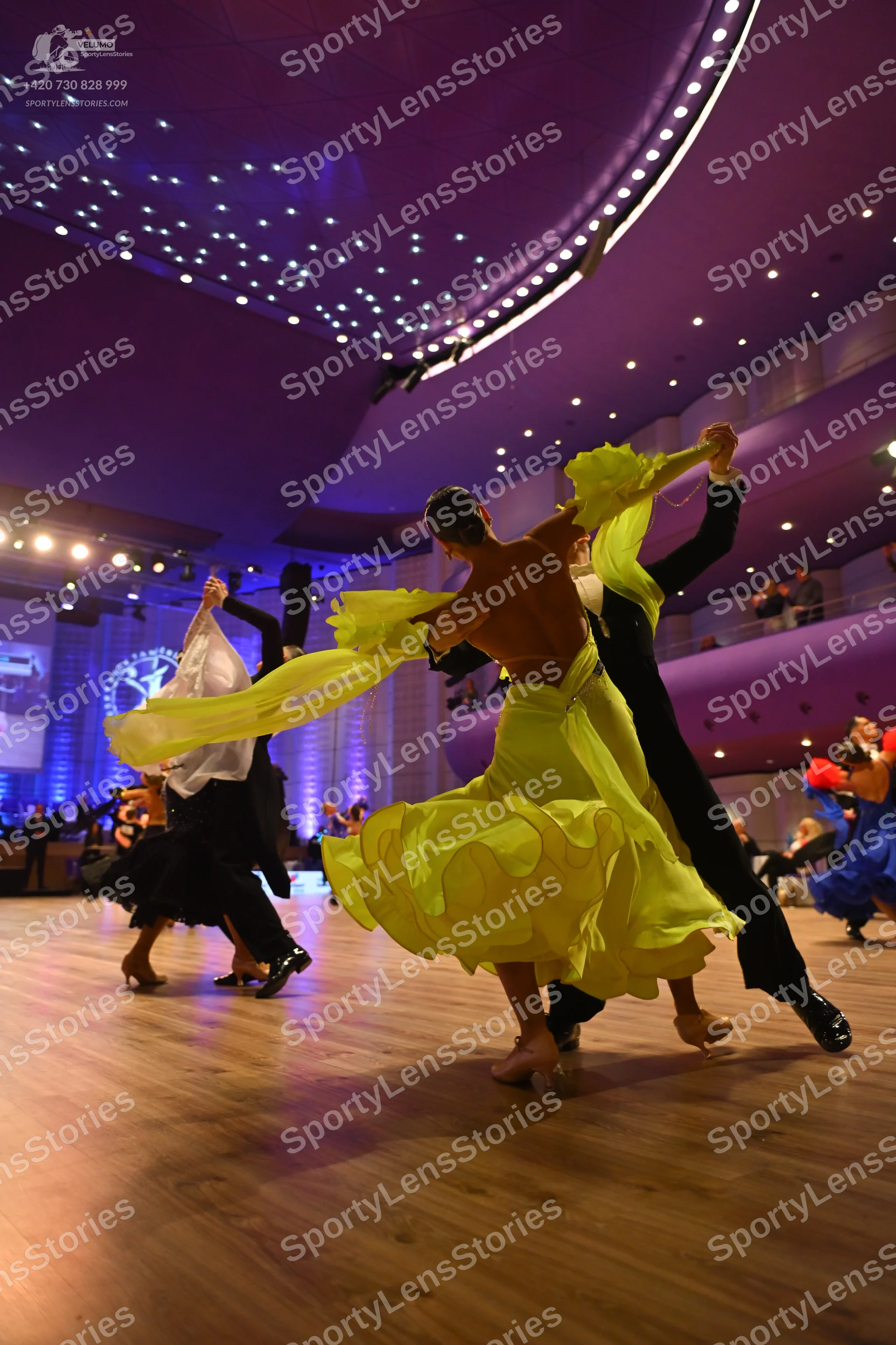 Dancesport competitor: Male dancer (foreground): black trousers and black dance shoes, appearing bare-c