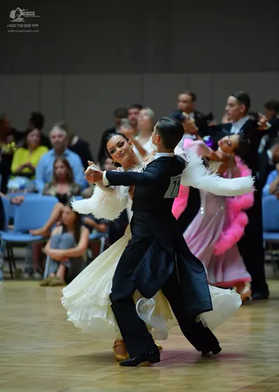 Dancesport competitor: Male dancer: black suit with white feathery trim on the sleeves and a white shir