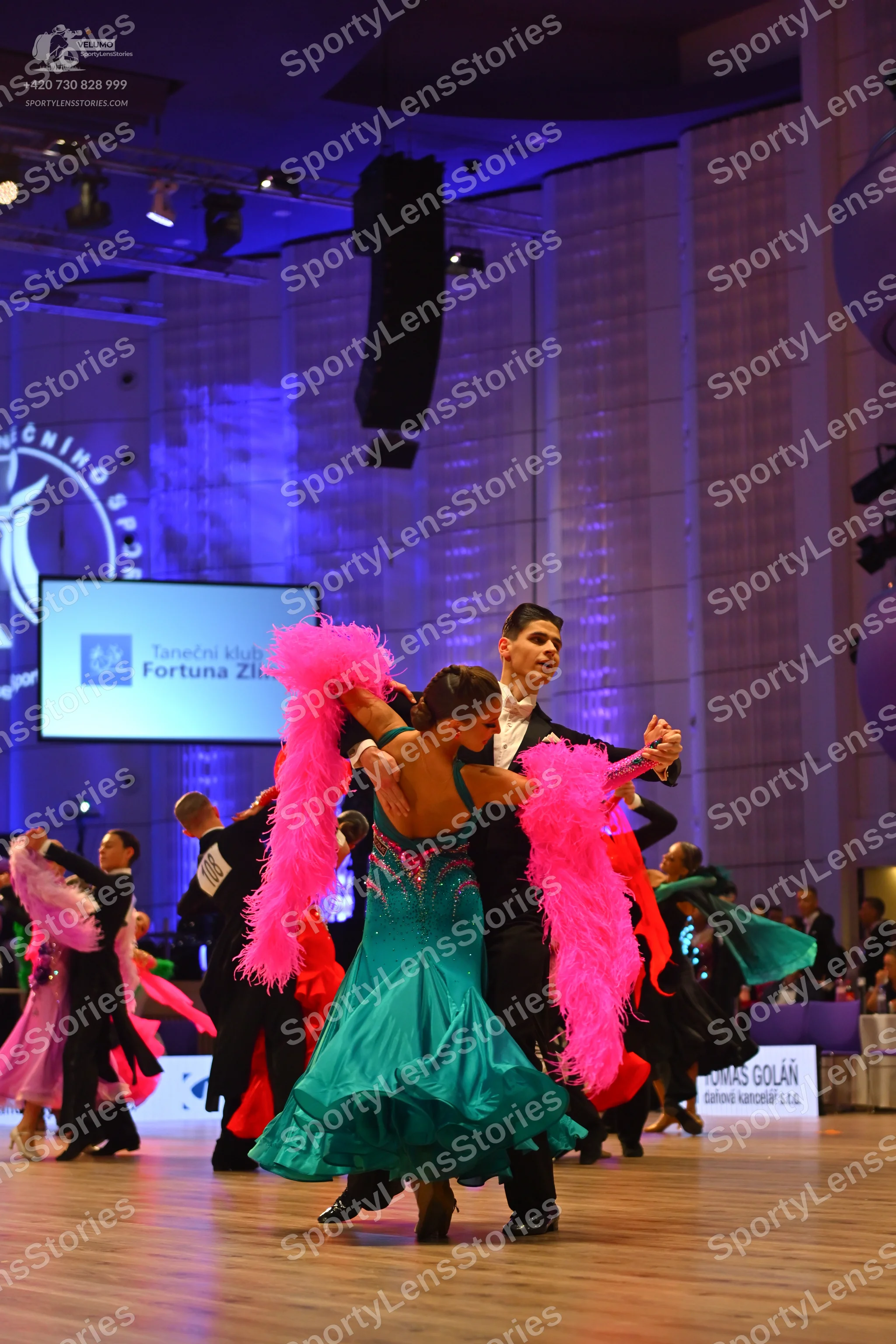 Dancesport competitor: Main female dancer: teal ballroom dress with a sequined bodice and a flowing ski