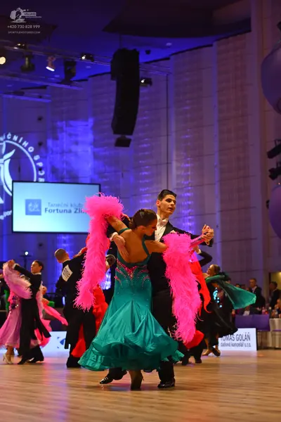 Dancesport competitor: Main female dancer: teal ballroom dress with a sequined bodice and a flowing ski