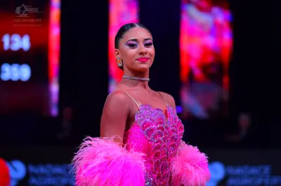 Dancesport competitor: Female dancer: pink latin dress with sequins and large pink feather sleeves