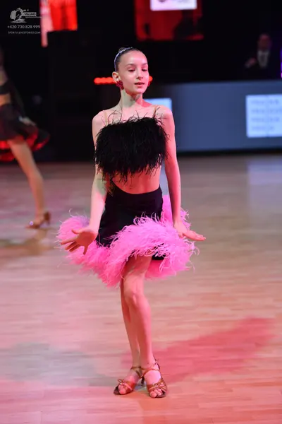 Dancesport competitor: Female dancer in foreground: black and pink feathered latin dress with a black f