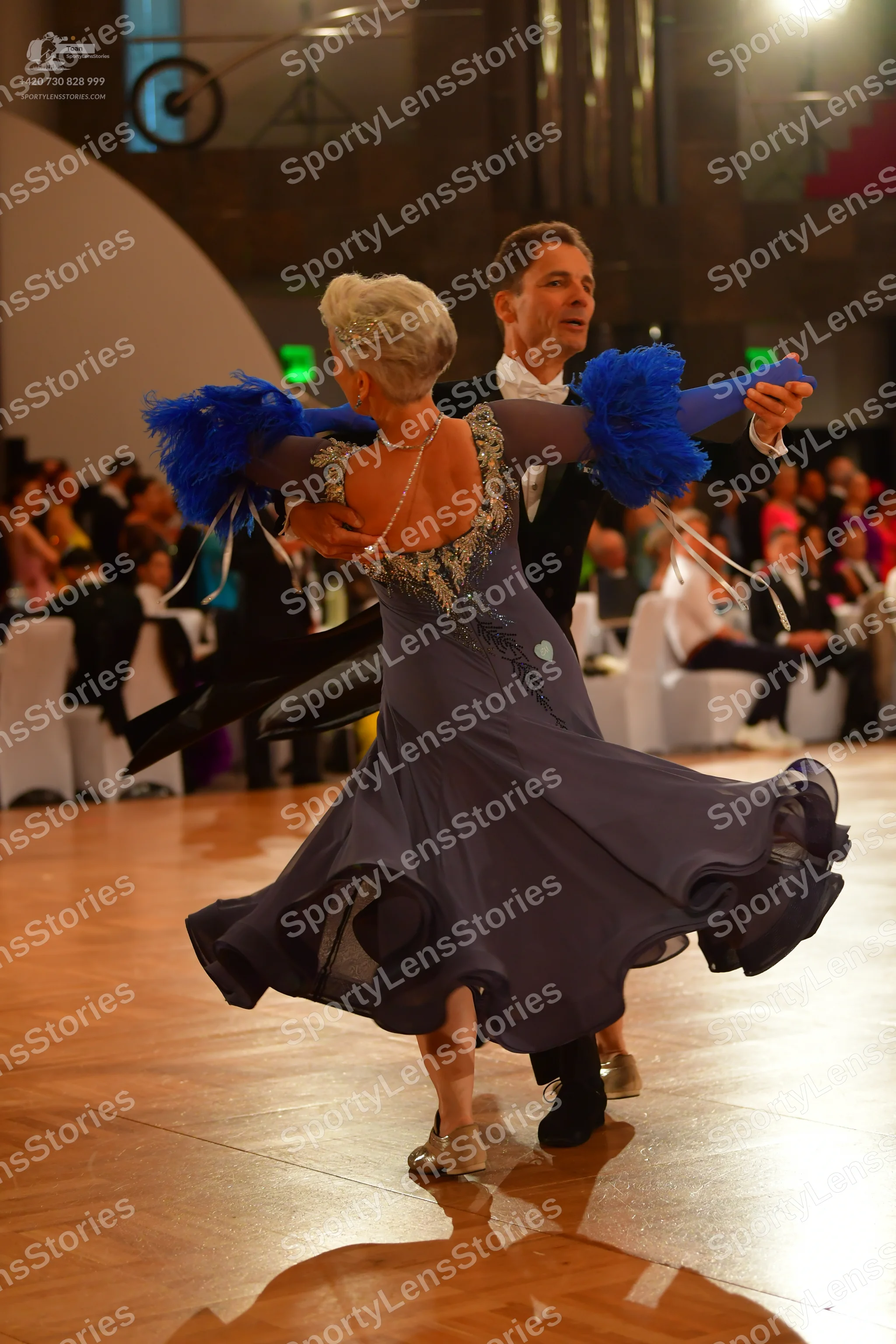 Dancesport competitor: Female dancer: flowing slate blue ballgown with a sequined neckline and back, an