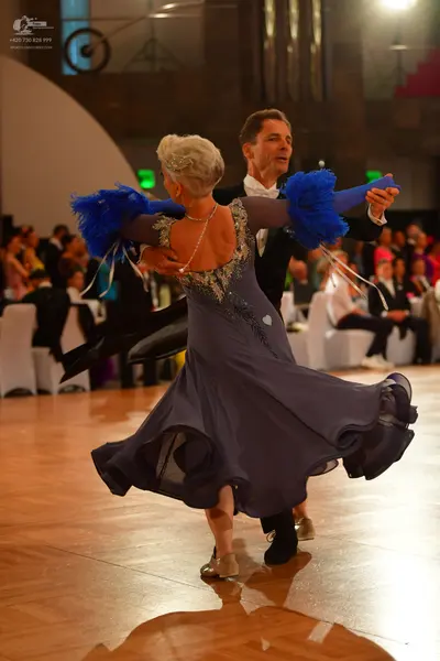 Dancesport competitor: Female dancer: flowing slate blue ballgown with a sequined neckline and back, an
