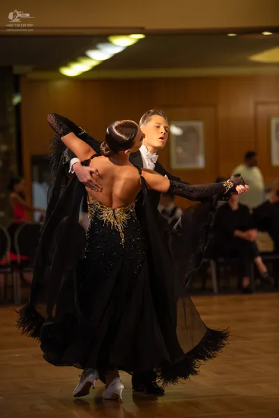 Dancesport competitor: Female dancer: black ballroom gown with gold sequin embroidery on the bodice, sh