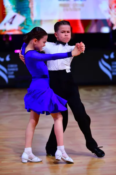 Dancesport competitor: Male dancer: white long-sleeved shirt with a black bowtie, black trousers, and b