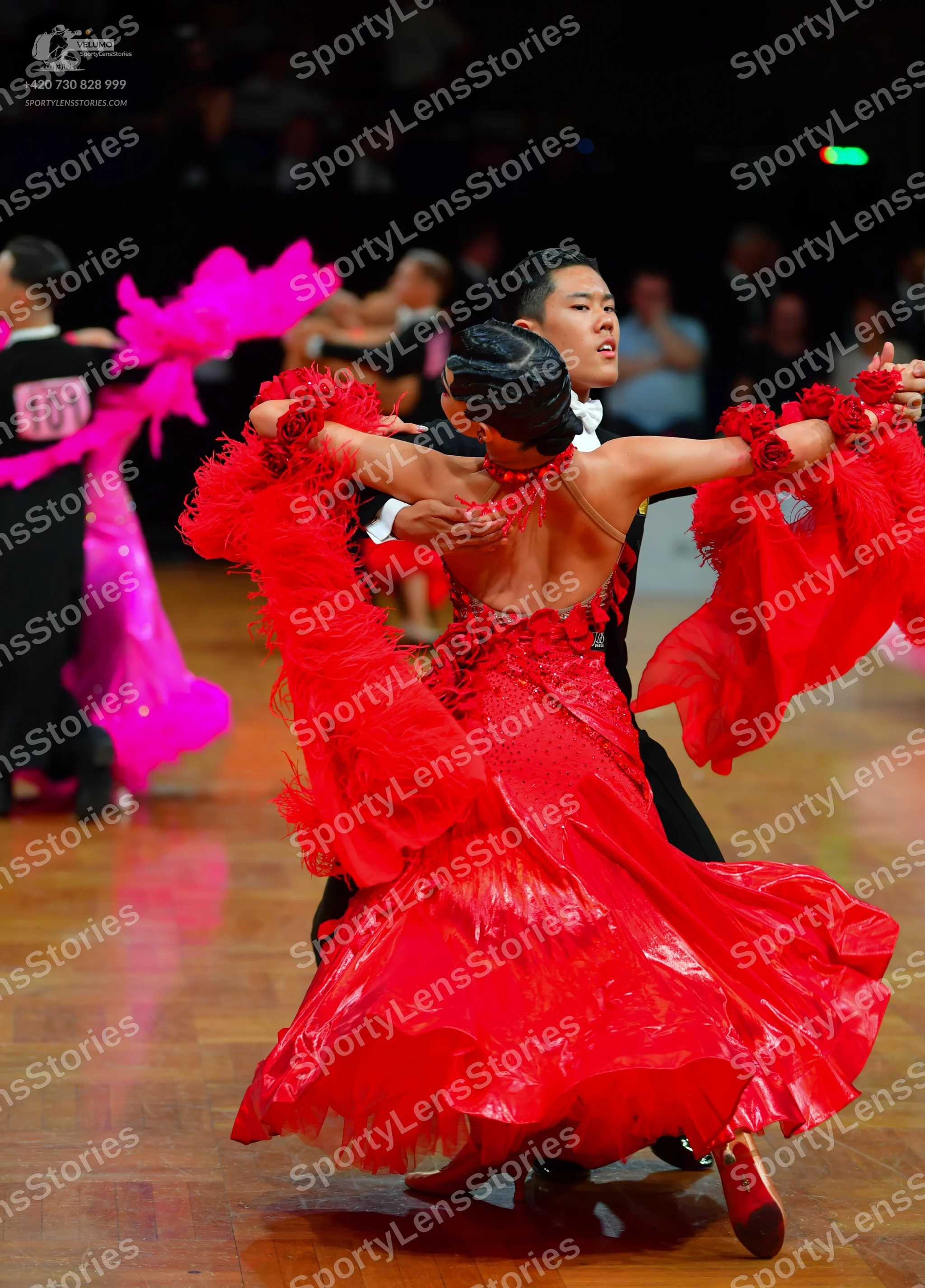 Dancesport competitor: Dancer on the left: black suit with a bright pink ruffled dress