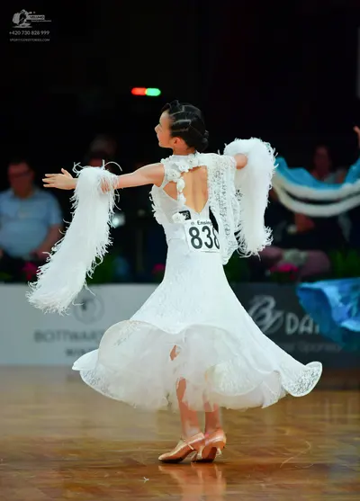 Dancesport competitor: Female dancer: white ballgown with lace detailing and large white feather-like a