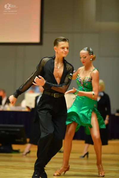 Dancesport competitor: Male dancer: black long-sleeved shirt with mesh sleeves, black trousers, a black