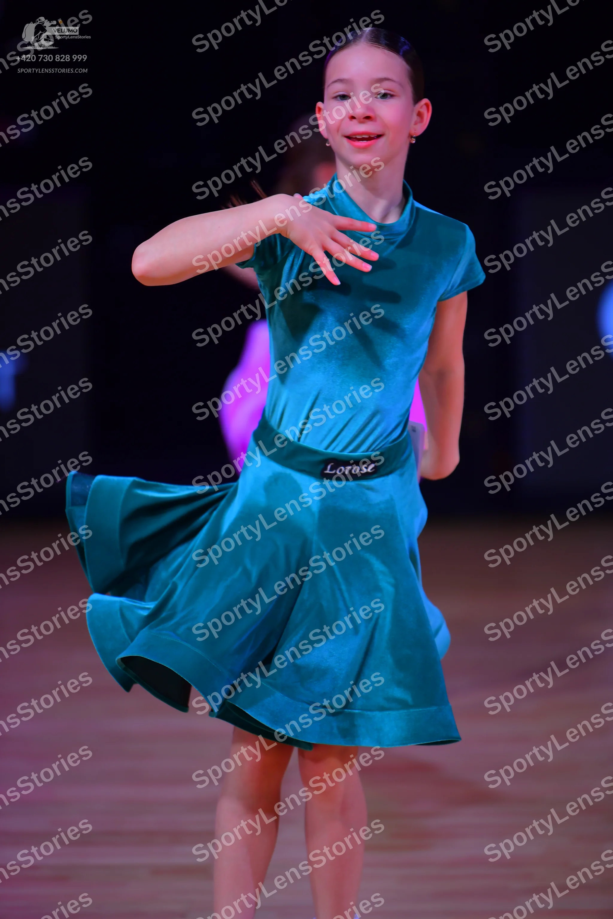 Dancesport competitor: Female dancer: teal satin-like short-sleeved dress with a flared skirt and a wid