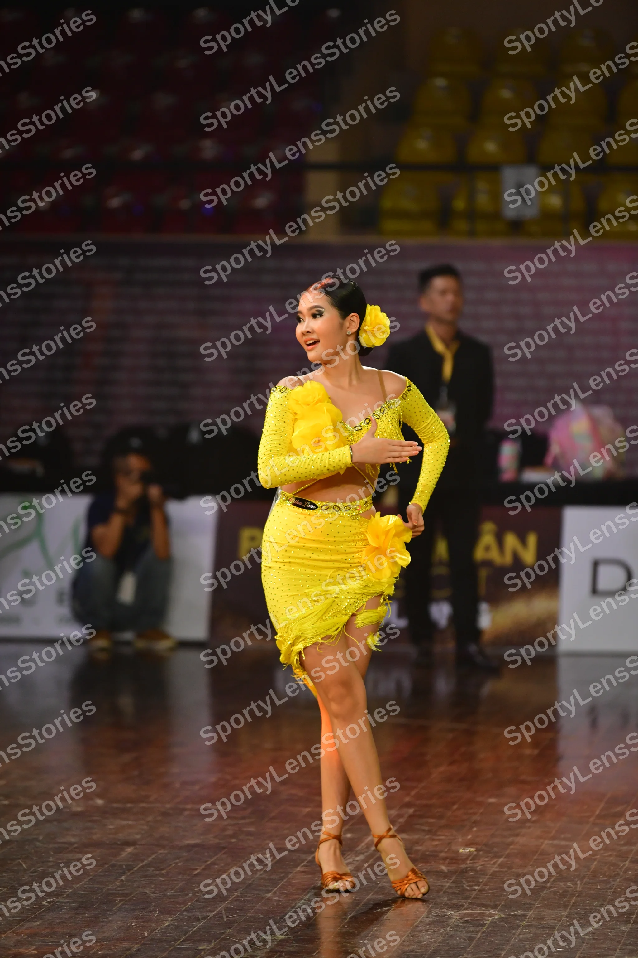 Dancesport competitor: Female dancer: yellow Latin dance dress with long sleeves and a ruffled skirt