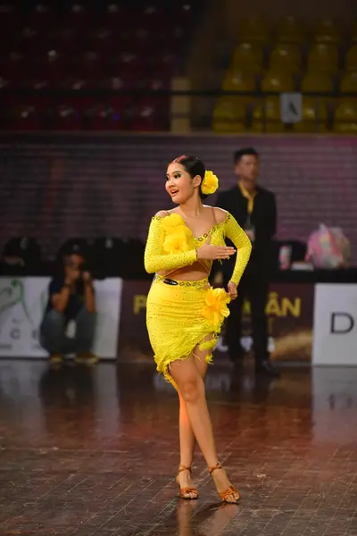Dancesport competitor: Female dancer: yellow Latin dance dress with long sleeves and a ruffled skirt