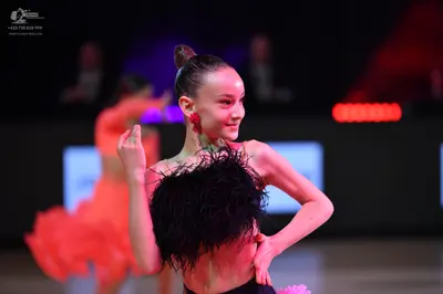 Dancesport competitor: Female dancer in foreground: black latin costume with thick black feather or fri