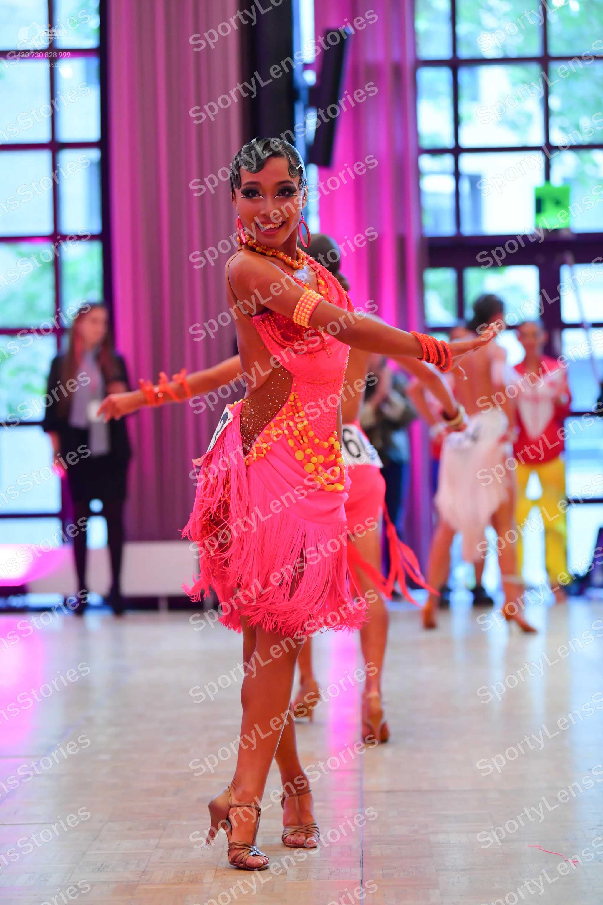Dancesport competitor #60: Main dancer: bright pink Latin dress with heavy fringe and gold sequin patterns
