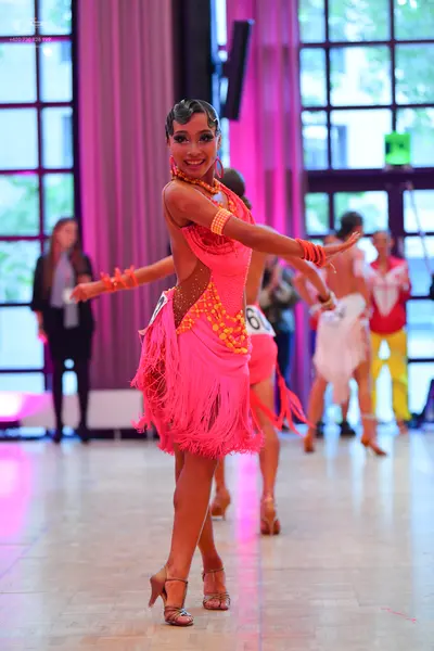 Dancesport competitor #60: Main dancer: bright pink Latin dress with heavy fringe and gold sequin patterns
