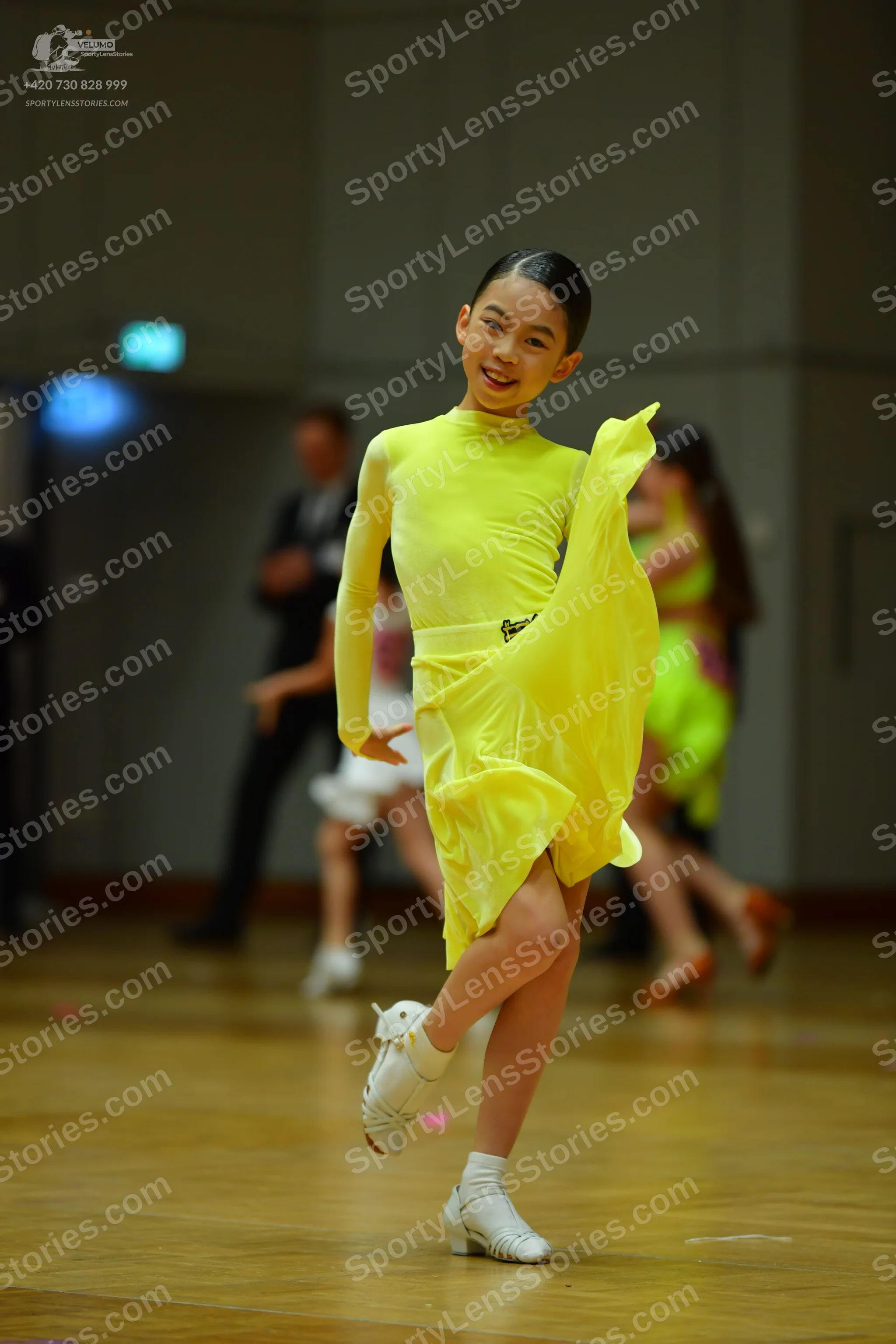 Dancesport competitor: Female dancer: yellow long-sleeved latin dress with a flowing skirt