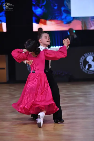 Dancesport competitor: Female dancer: bright pink satin-like ballroom gown with long sleeves