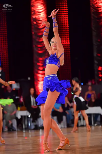 Dancesport competitor: Female dancer (center): electric blue two-piece latin costume with sequin embell