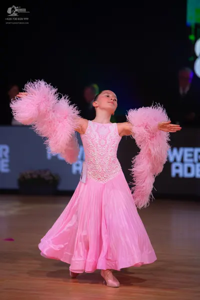 Dancesport competitor: Female dancer: light pink ballroom gown with a lace-patterned bodice and a volum