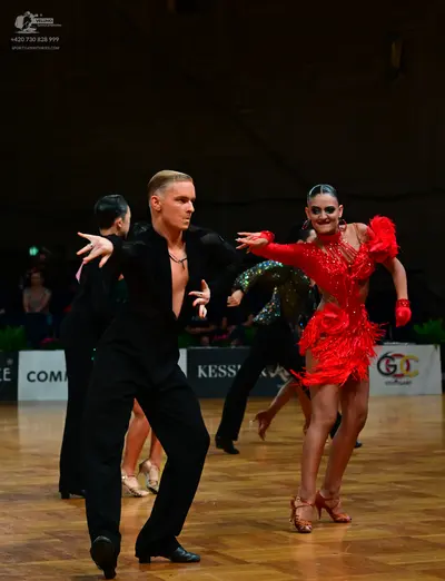 Dancesport competitor: Male dancer in foreground: black long-sleeved shirt and black trousers