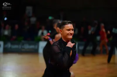 Dancesport competitor: Male dancer: black long-sleeved top with possible sequin or mesh details