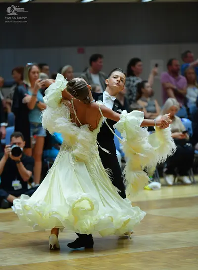 Dancesport competitor: Female dancer: pale yellow voluminous ballroom dress with many ruffled, layered 