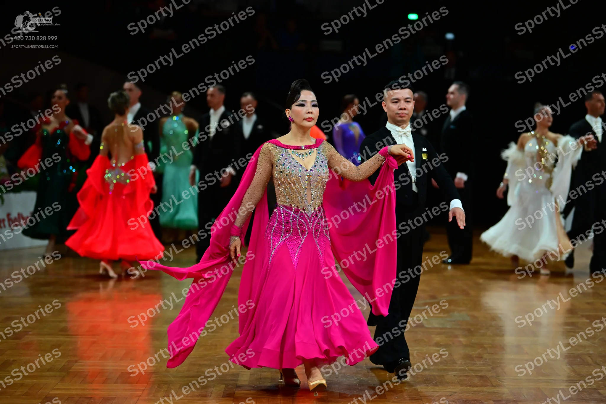 Dancesport competitor: Female dancer in center: vibrant pink ballroom dress with a nude mesh bodice fea