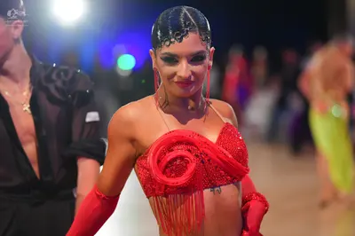 Dancesport competitor: Female dancer: red Latin dress with sequins and long fringe, wearing matching lo
