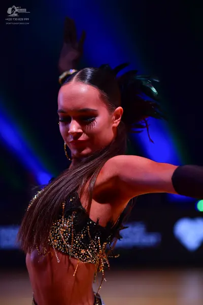 Dancesport competitor: Female dancer: black latin crop top decorated with sequins and gold/yellow dangl