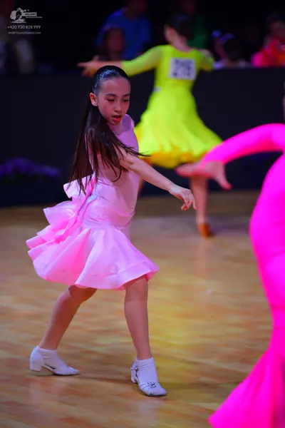 Dancesport competitor: Female dancer in foreground: pink latin dress with a flared skirt