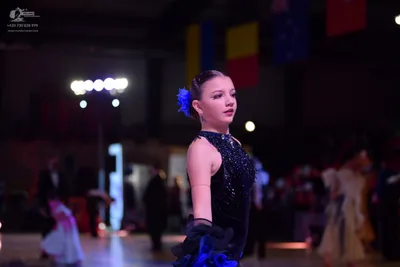 Dancesport competitor: Female dancer in foreground: black sleeveless latin dress with sequins and a blu